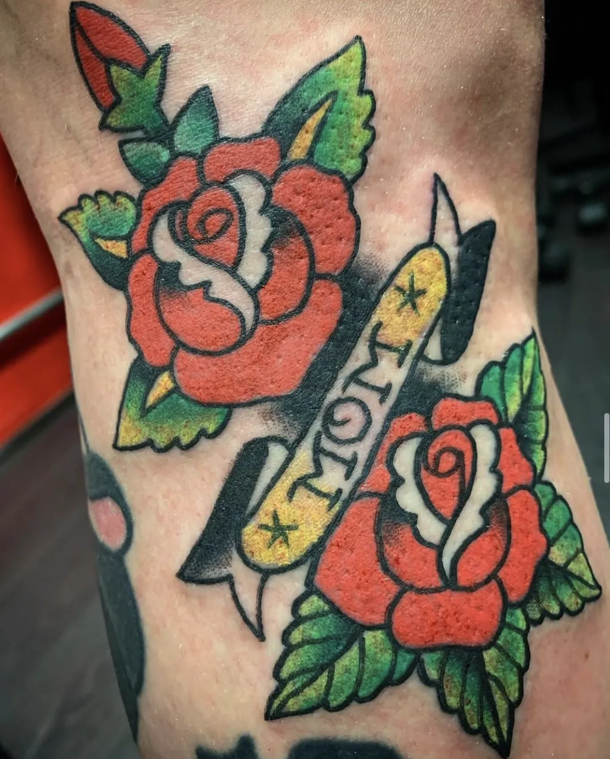 Two red traditional roses with a scripted ribbon banner