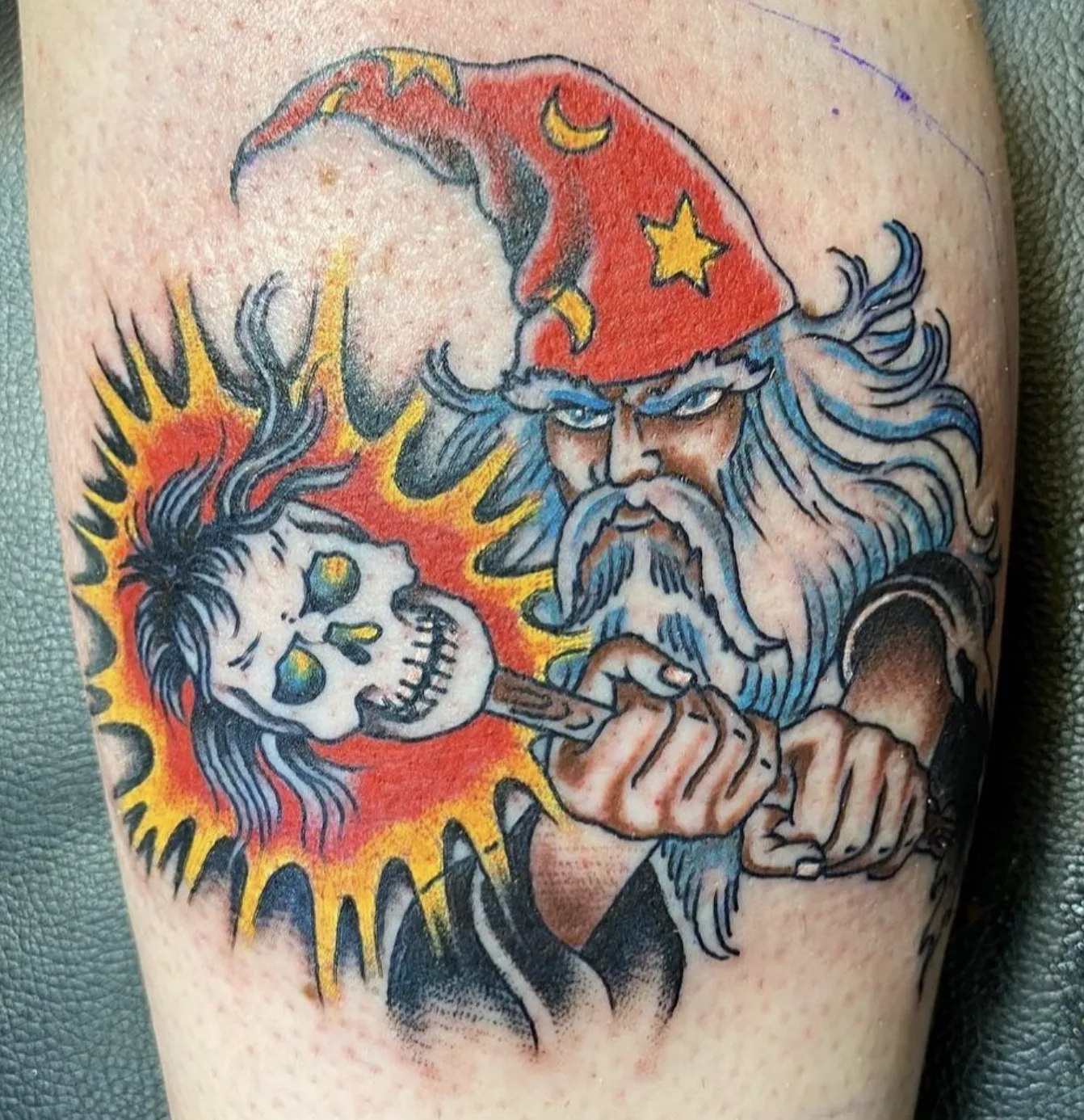 Wizard in a red starred cap holding a flaming skull-topped staff